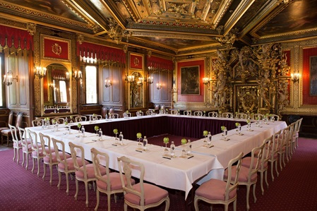 Goldener Saal für Tagung eingedeckt mit rosa weißen Stühlen