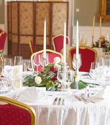 Festlich dekorierter Gartensaal mit Blumenschmuck und Kerzenleuchtern auf den Tischen