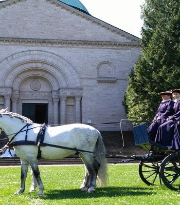 Kutsche mit zwei Pferden und gewandeten Reitern vor dem Mausoleum